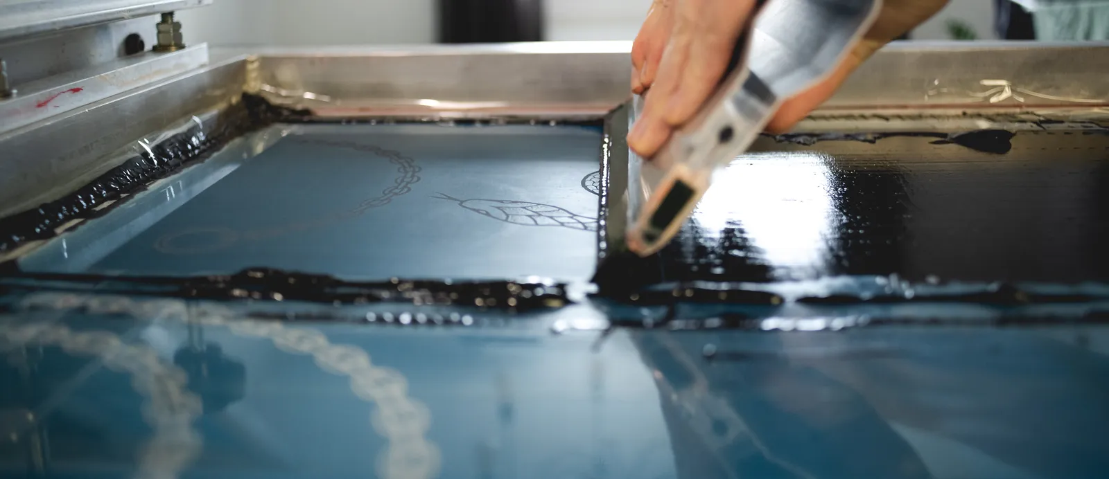 Deep blue ink being flooded across a detailed screen in the studio
